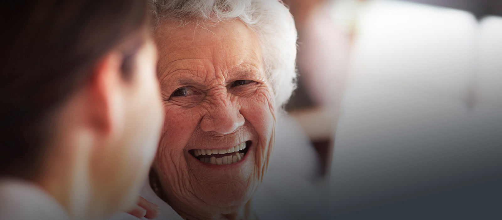 Image of an old lady smiling at her caregiver